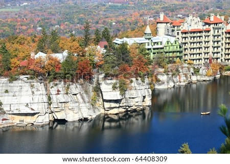 White Sandstone congrolomerate cliffs stand over Mohonk Lake next to Mohonk Mountain House resort with a colorful autumn hillside behind