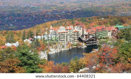 Postcard view of Mohonk Lake and Mohonk Mountain House resort surrounded by sandstone cliffs and colorful Autumn trees in the Shawangunk Mountains of New York