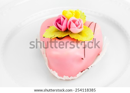 Single cake decorated with flowers on a plate in front of white background