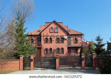 A large red brick built country house with a tiled roof