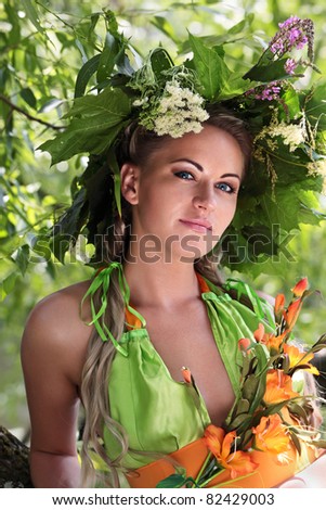 Portrait of a young girl with the diadem of flowers and leaves on his head on a green background, dressed up for the holiday of Ivan Kupala (John Baptist's Day)