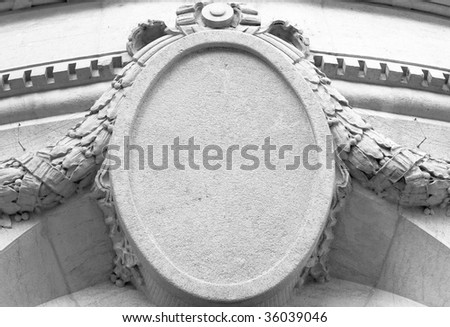 Details of carved old stone oval shaped plaque sign on building.