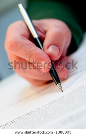 hand with pencil signing the document