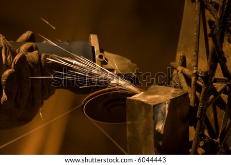 Closeup of factory worker holding grinder in leather gloves