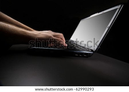 typing on the keyboard of a laptop against a black background