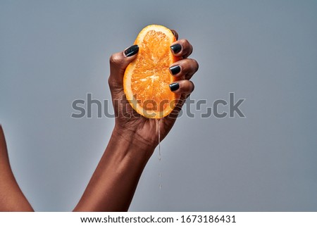 Female hand squeezing orange isolated on grey. Copy space Сток-фото © 