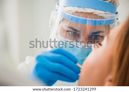 Young female dentist curing patient's teeth filling cavity. Stomatologist working with professional equipment in clinic office. Close-up shot, teeth care and medicine concept
