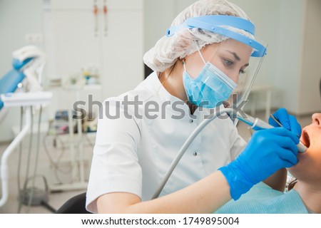 Female dentist curing teeth cavity in blue gloves and protective mask. Dentist caries treatment at dental clinic office. People, medicine, stomatology and health care concept Stockfoto © 