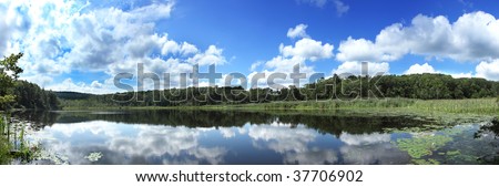 Panoramic pond view in summer,clouds reflected in still pond`s water