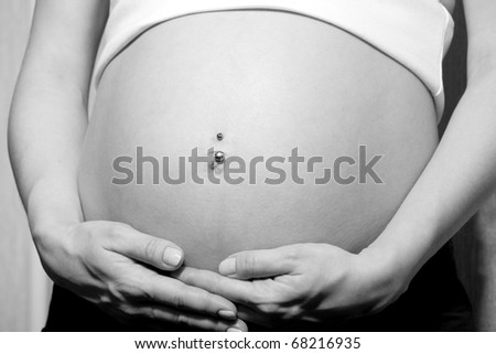 Image of pregnant woman touching her belly with hands. Black and white color