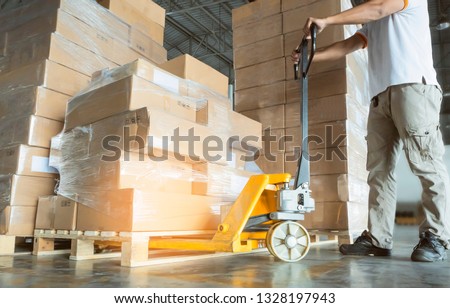 Young man with hand pallet truck or pallet jack and stack of cardboard boxes on pallet in distribution warehouse. ストックフォト © 