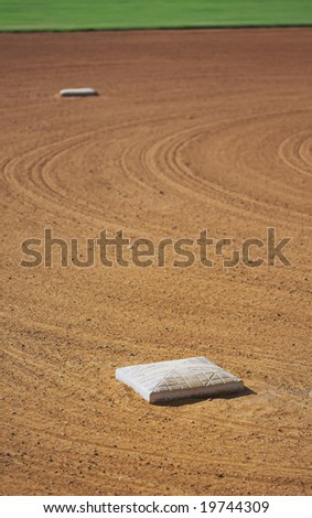 Second (distance) and third (focus) bases on a baseball diamond. Shallow depth of field.