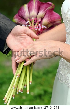 Wedding bouquet of violet calla and hands of groom and bride