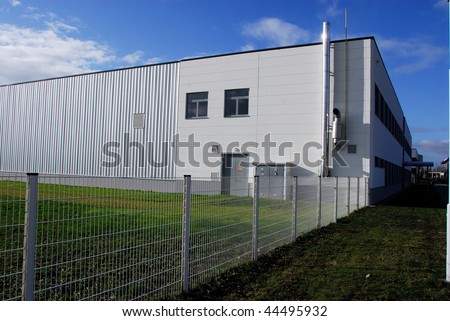 Modern white factory building with wired fence