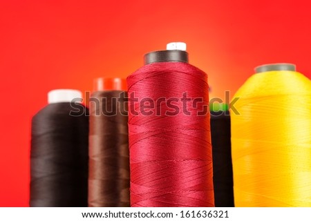 Multicolored Spools of Thread on Red Background