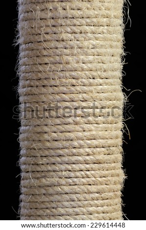 A close-up of sisal rope scratching pole for cats on a black background