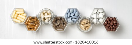 Various capsules and pills with dietary supplements or medicines in hexagonal jars are in the form of a honeycomb