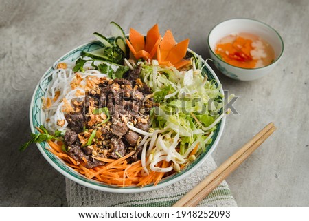 A large bowl of traditional South Vietnamese noodle dish called Bun Bo Nam Bo with beef, noodles, fresh herbs, pickled vegetables and fish sauce. Stok fotoğraf © 