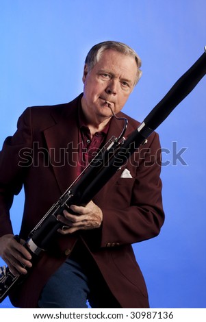 A bassoon musician performing against an isolated blue background with copy space in the vertical format.