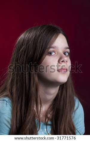 Teenage girl looking sideways isolated against a dark red background the vertical format.