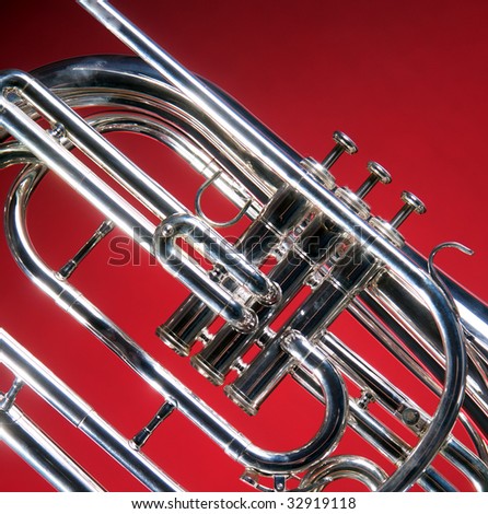 A marching French horn up close isolated against a red  back ground in the square format with copy space.