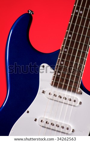 A blue color electric guitar isolated against a red background in the vertical format with copy space.