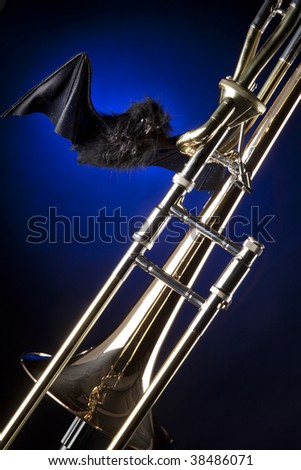 A Halloween trombone and bat isolated against a blue spotlight background in the vertical format.