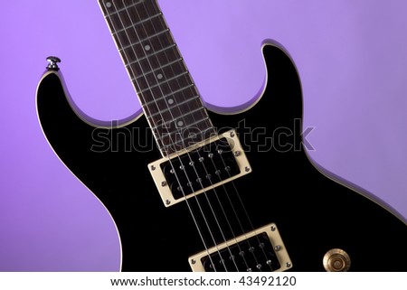 A piano finish black electric guitar close up isolated on  a purple background in the horizontal format.