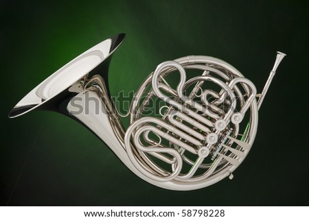 A professional double French horn isolated against a spotlight green background.
