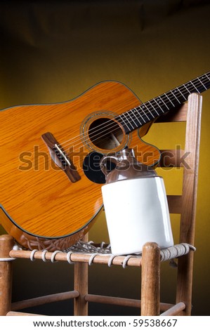 An old potter ceramic country jug with a guitar and rope bottom chair on a gold background in  the  vertical format with copy space.