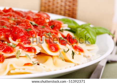 Fresh and tasty bowtie pasta with tomato marinara sauce and basil garnish