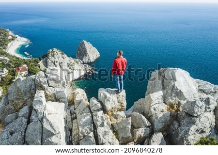 Aerial view of man tourist in red jacket standing on the rock top of cat mountain enjoying landscape of Simeiz with Diva and Penea rocks in background. Crimea 商業照片 © 