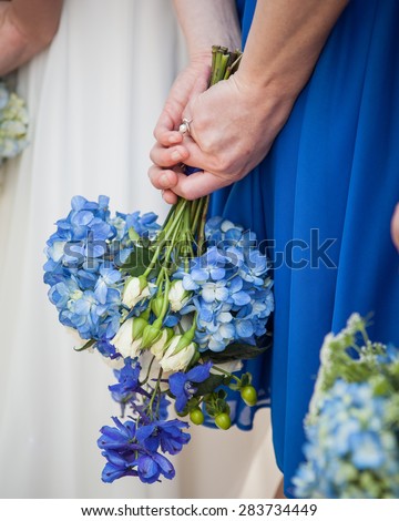bridesmaid holding a blue hydrangea bouquet against her blue dress behind her back