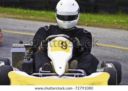 Drivers racing high speed around a track in a go-kart