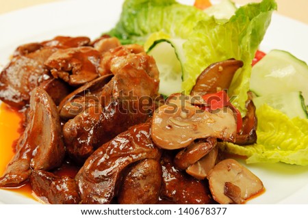 Roasted liver with sauce, lettuce and cucumber on dish in the restaurant