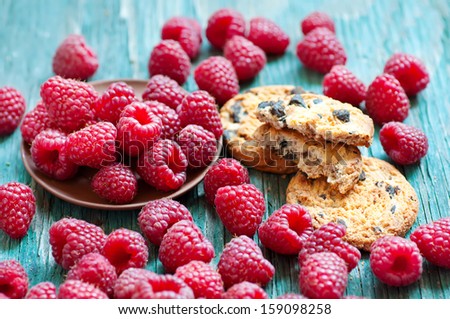 Fresh raspberry on the blue wooden rustic desk with cookies