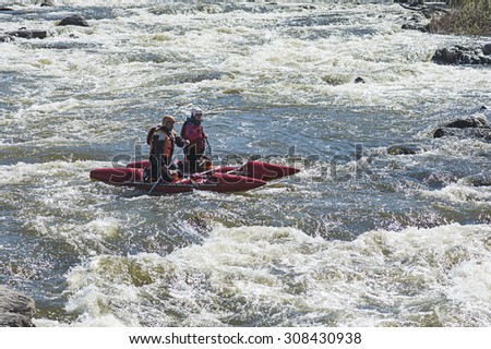 SOUTHERN BUG RIVER, UKRAINE - MARCH 30, 2014: Sport catamaran is fused on the rapid river with two persons
