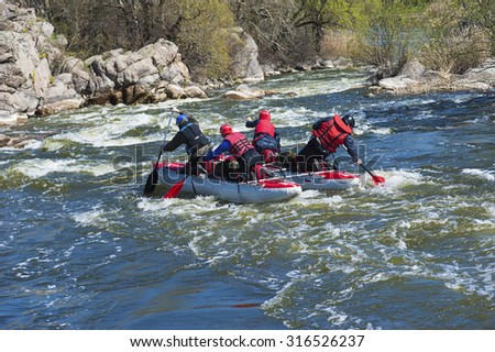 SOUTHERN BUG RIVER, UKRAINE - MARCH 30, 2014: Sport catamaran is fused on the rapid river with two persons