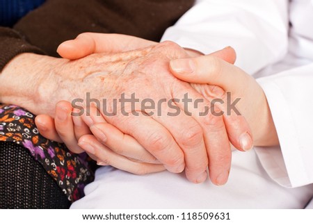 Young sweet doctor holds the old woman hands