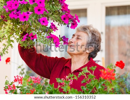 Happy old lady smell her colorful flowers