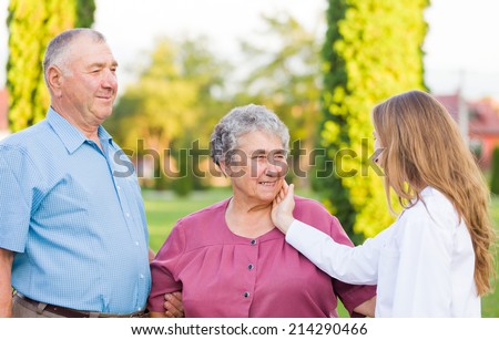 Happy elderly couple with their carer in the nature