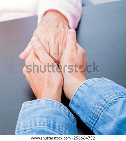 Young carer giving helping hands for elderly woman