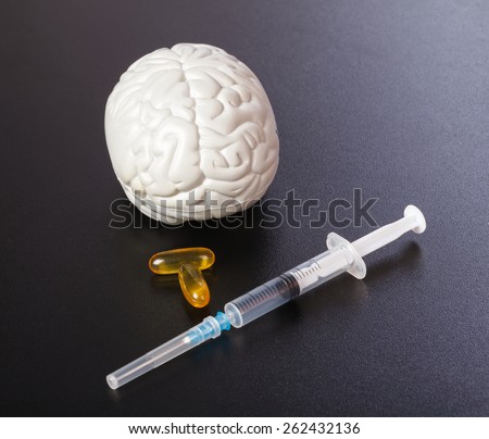 Plastic brain injection and omega 3 capsules on isolated black background