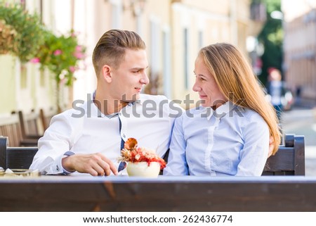 Happy young couple sitting outside in restaurant and talking