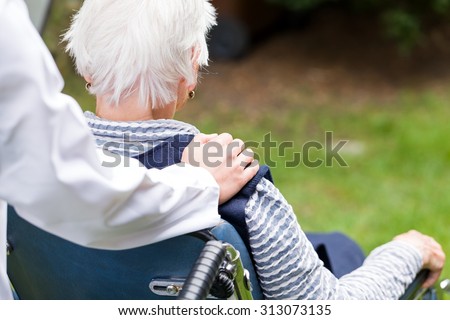 Photo of young carer pushing the elderly woman in wheelchair