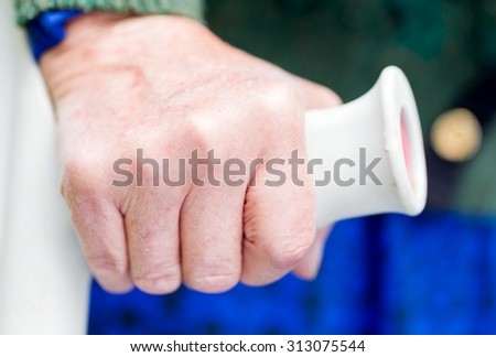 Close up photo of elderly womans hand resting on crutch