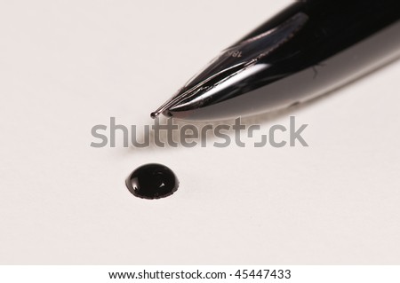 Closeup of pen nib and ink drop on paper