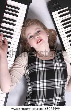 Teenage musician lying on the floor between two keyboards.