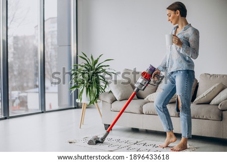 Woman with accumulator vacuum cleaner drinking coffee