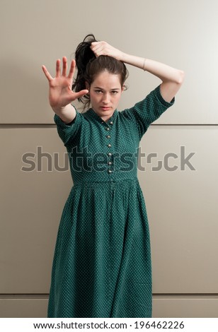 Natural female model poiting her hand to the camera white grasping her hair